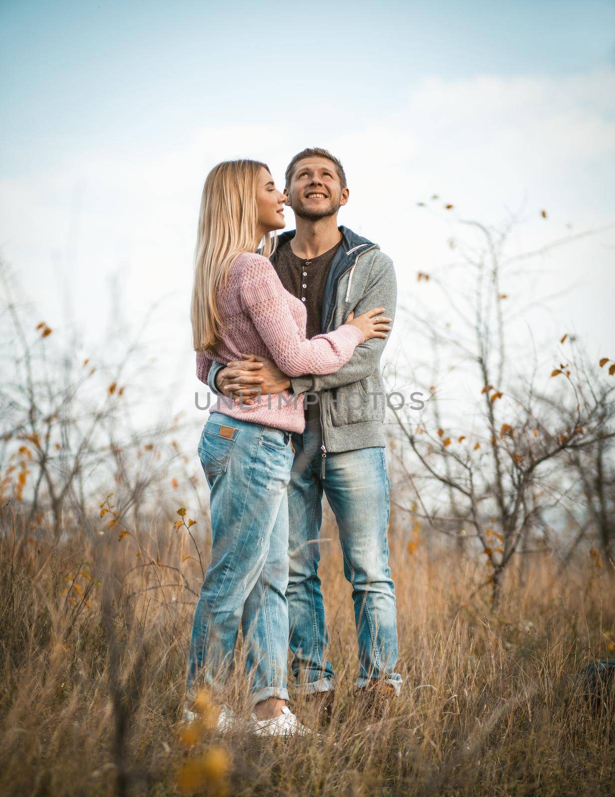 Man And Woman Stands Embracing On Grass Outdoors by LipikStockMedia