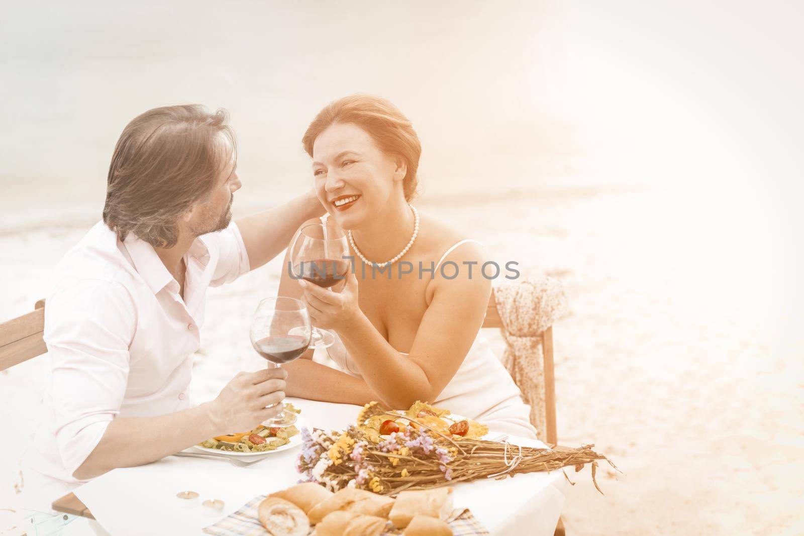 Mid aged couple with red wine sit in restaurant in beautiful style. Happy elderly concept by LipikStockMedia