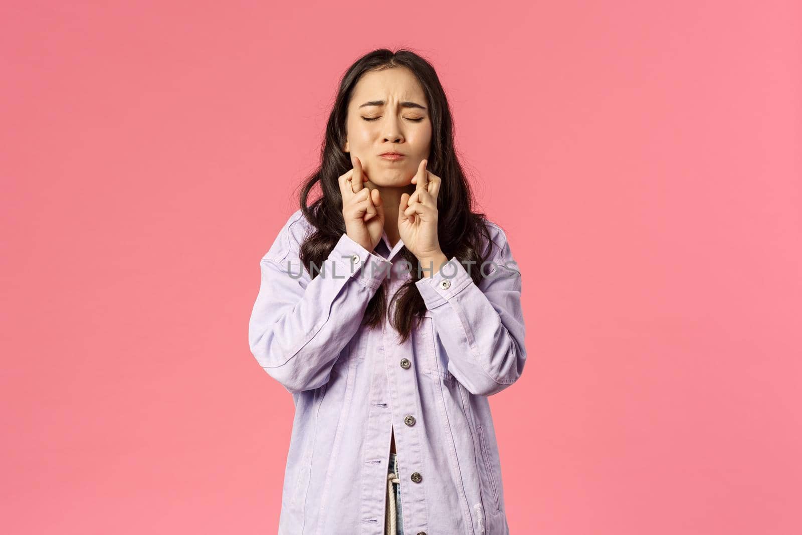 Portrait of woman desperately wants her dream to come true, cross fingers and close eyes, pouting pleading, praying god wish fulfill, standing pink background anticipate miracle happen with hope.