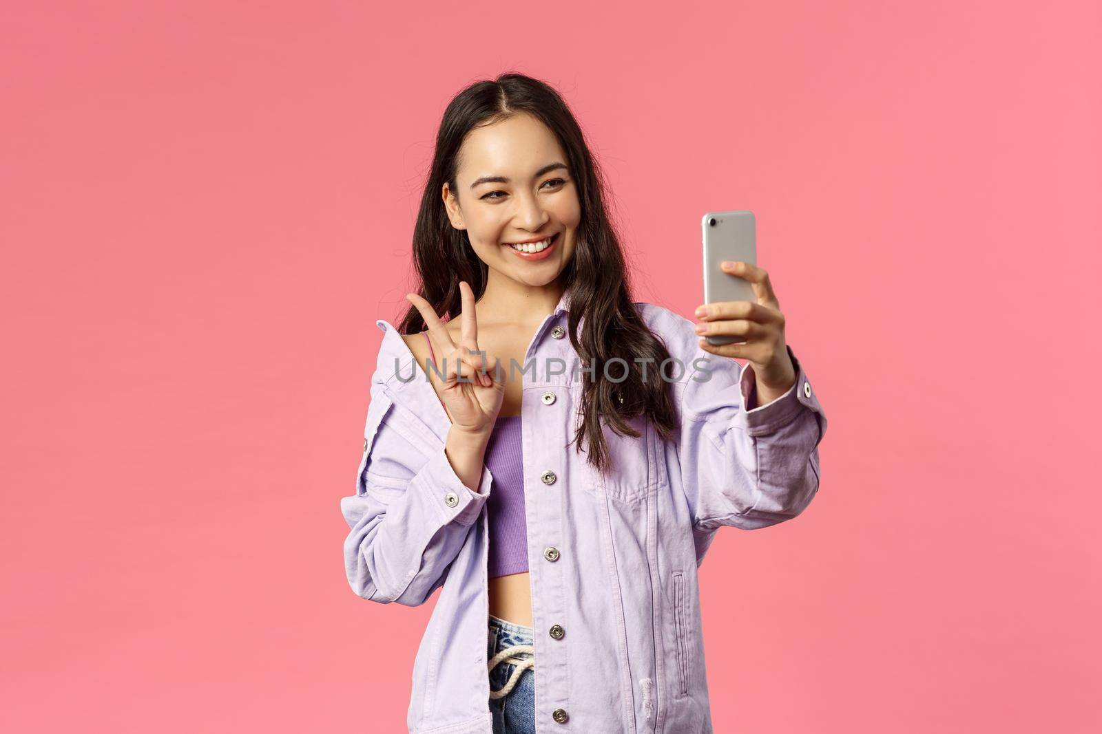 Online lifestyle, people and beauty concept. Stylish pretty korean girl talking to friend online video chat, messanger, taking selfie with photo filters app, show peace sign and smiling mobile phone.