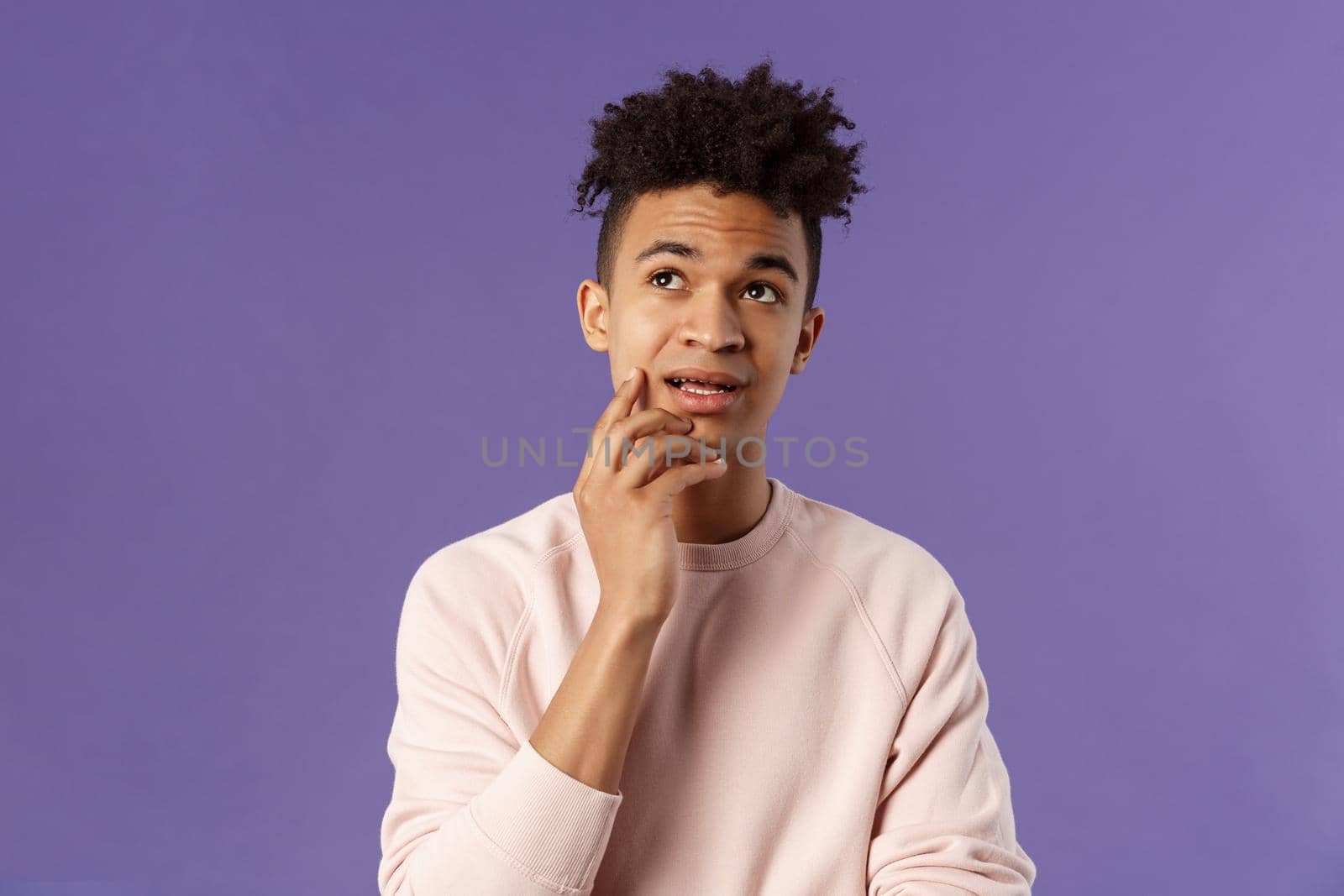 Waist-up portrait of thoughtful unsure young hispanic male student trying solve exercise, looking up thinking, pondering and calculating in mind, standing focused and indecisive purple background.