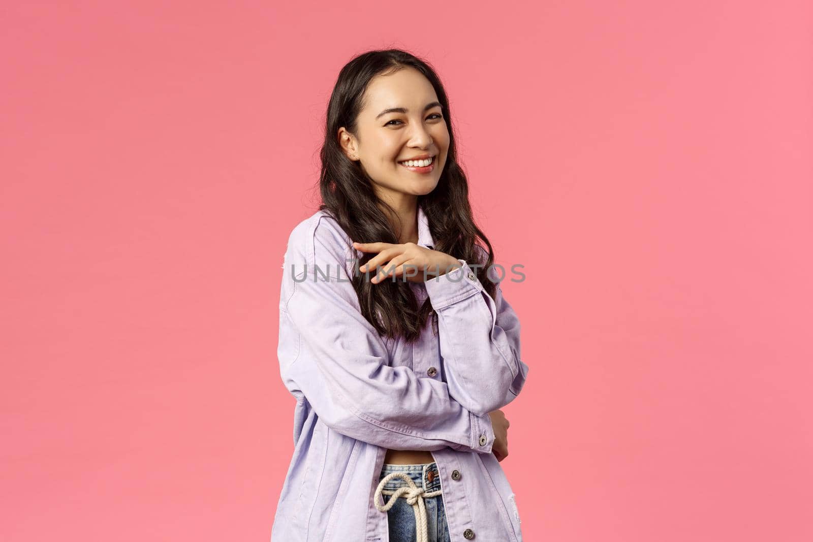 Oh stop it you make me blush. Portrait of silly stylish, good-looking korean girl giggle and talking to someone, hold hand near chest laughing having carefree conversation, pink background.