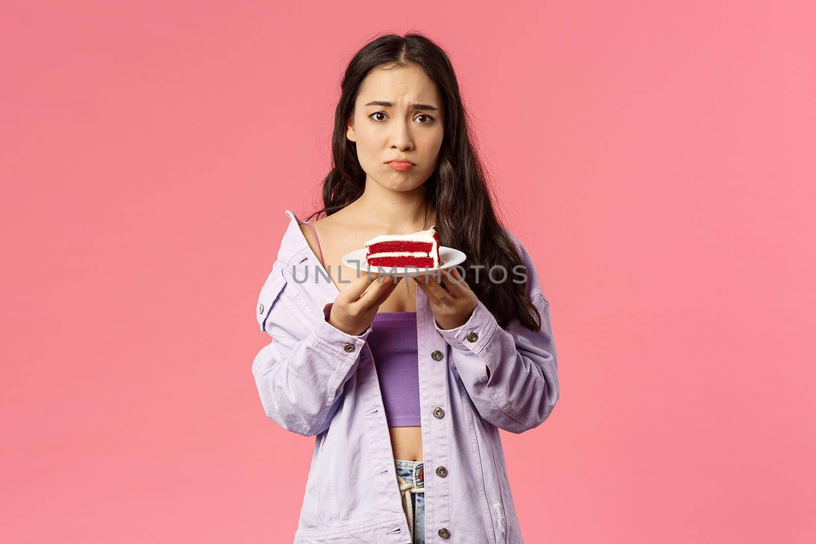 Portrait of gloomy sad cute asian girl just being dumped trying eat-out her sadness, holding piece cake, pouting and frowning upset, have uneasy feelings, grieving, pink background by Benzoix