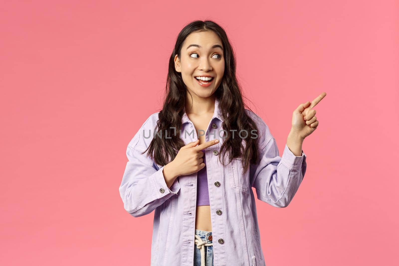 Portrait of curious, interested pretty asian woman in stylish outfit, pointing looking upper right corner with amused smile, see cool product, online courses or internet shopping advertisement by Benzoix