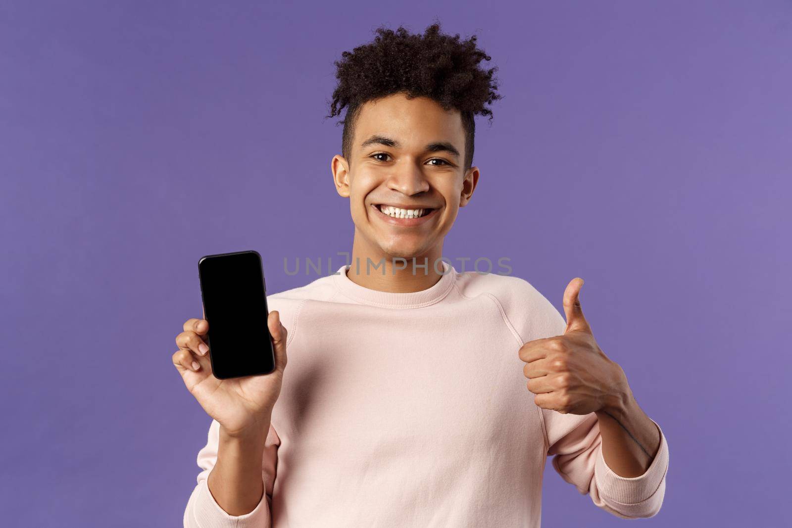 Close-up portrait of cheerful, satisfied young male customer recommend buying subscribtion to game or app, learning leanguage via application mobile phone, show thumb-up in approval by Benzoix