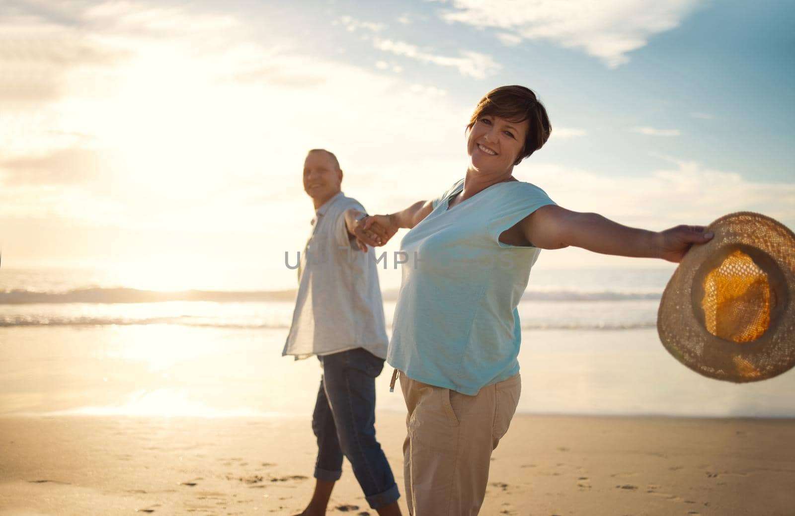 Were enjoying the best years of our life. a mature couple spending the day at the beach. by YuriArcurs