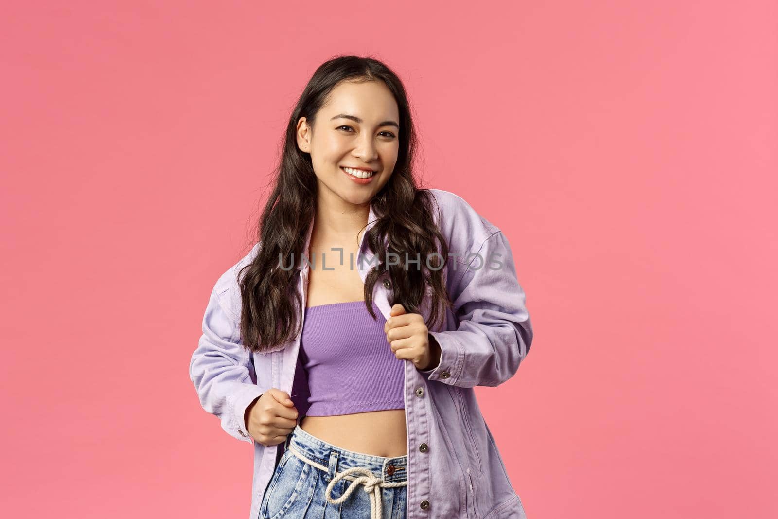 Portrait of enthusiastic girl chilling and vibing, dancing over favourite song, moving to rhythm music at awesome party or festival, smiling camera carefree and happy, pink background.