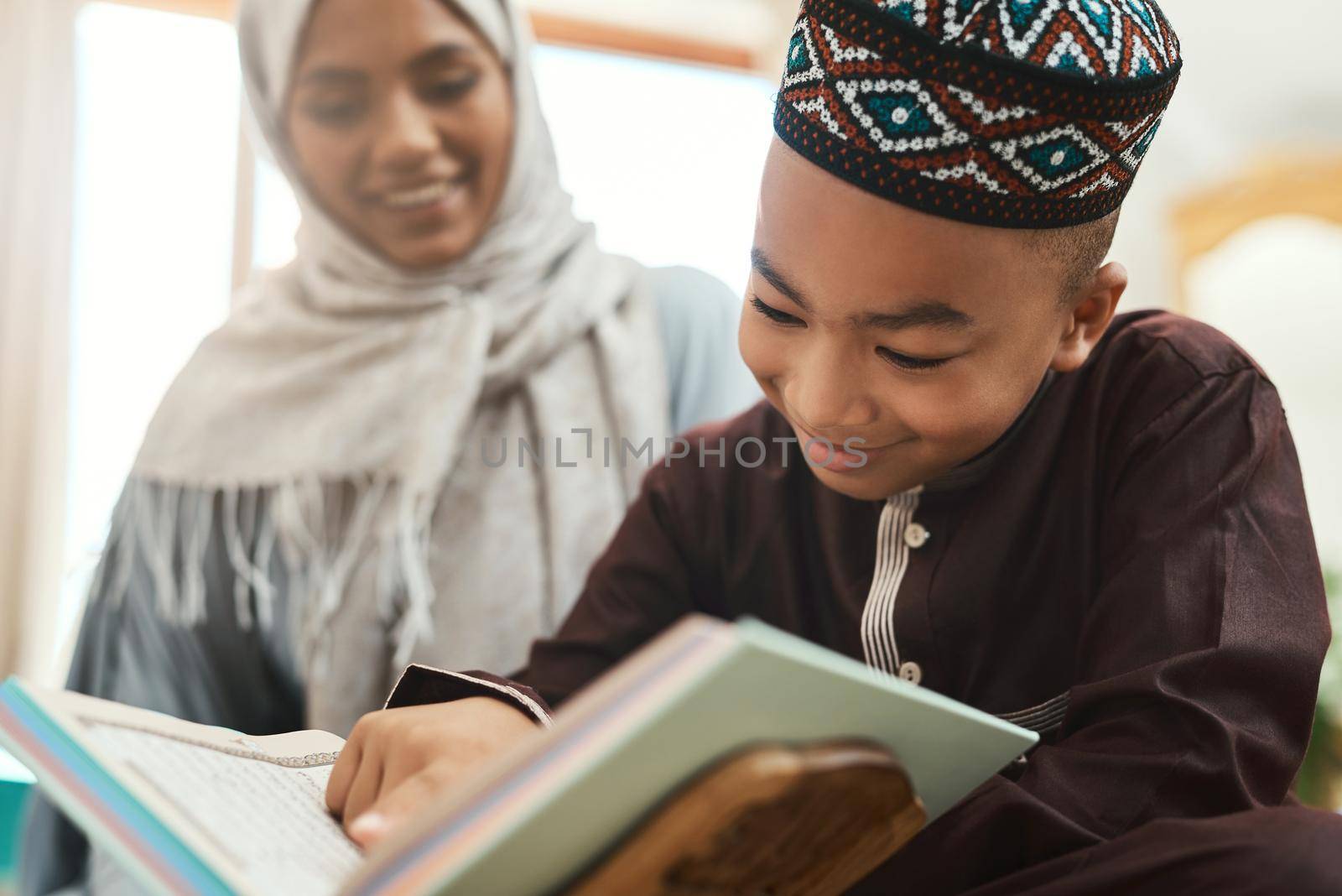Education is the lighting of a fire. a young muslim mother and her son reading in the lounge at home