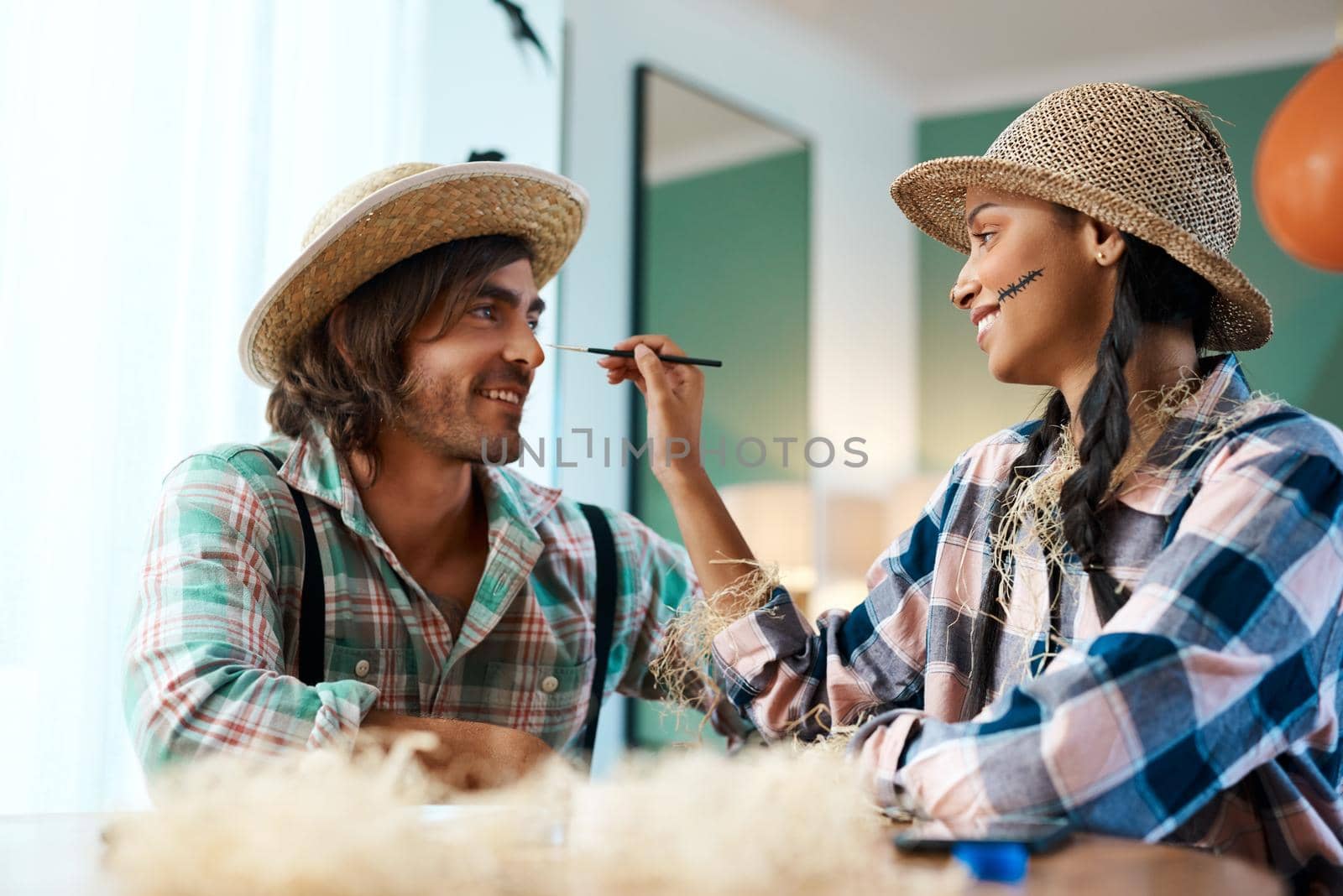 Ill make it as realistic as possible. a young woman applying makeup to a young man at home. by YuriArcurs