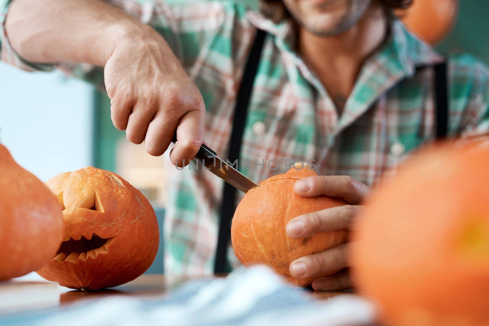 Carving the perfect pumpkin is a skill. a young man carving a pumpkin at home. by YuriArcurs
