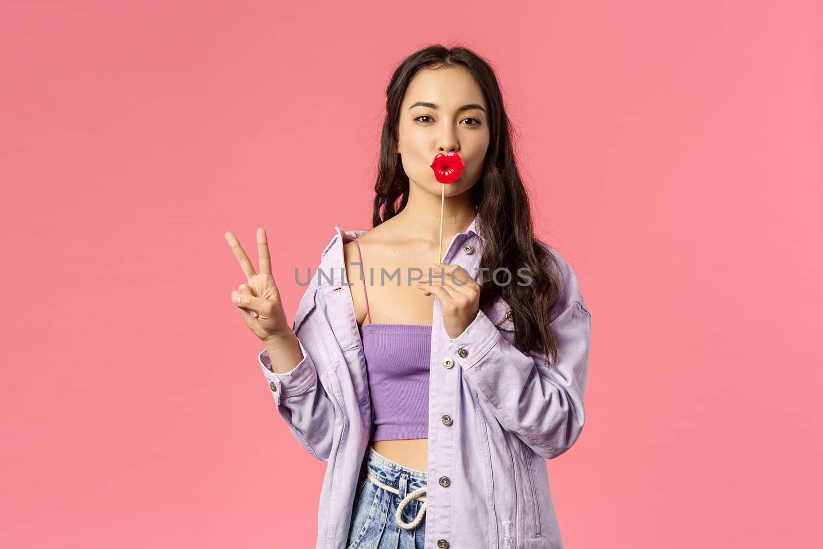 Holidays, lifestyle and people concept. Portrait of sassy good-looking, feminine asian woman in stylish outfit, holding big lips stick and show peace sign, standing pink background by Benzoix