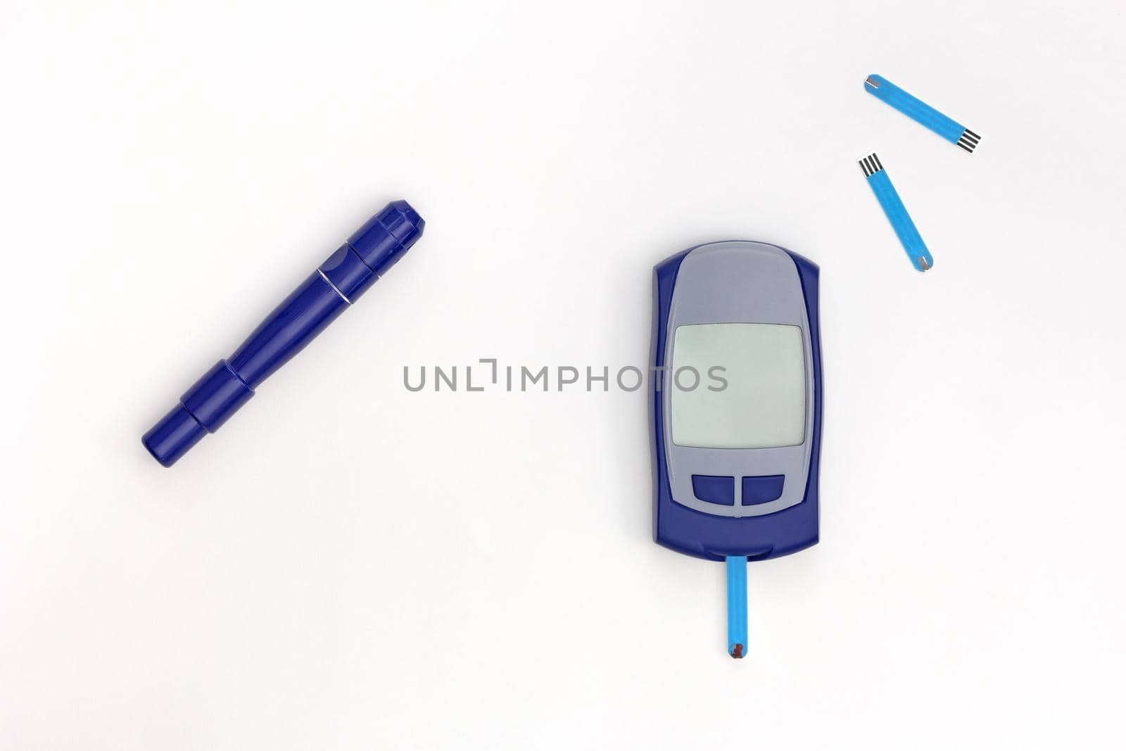 Top view of glucometer with blooded test strip inside and empty display, lancet and test strips on white background