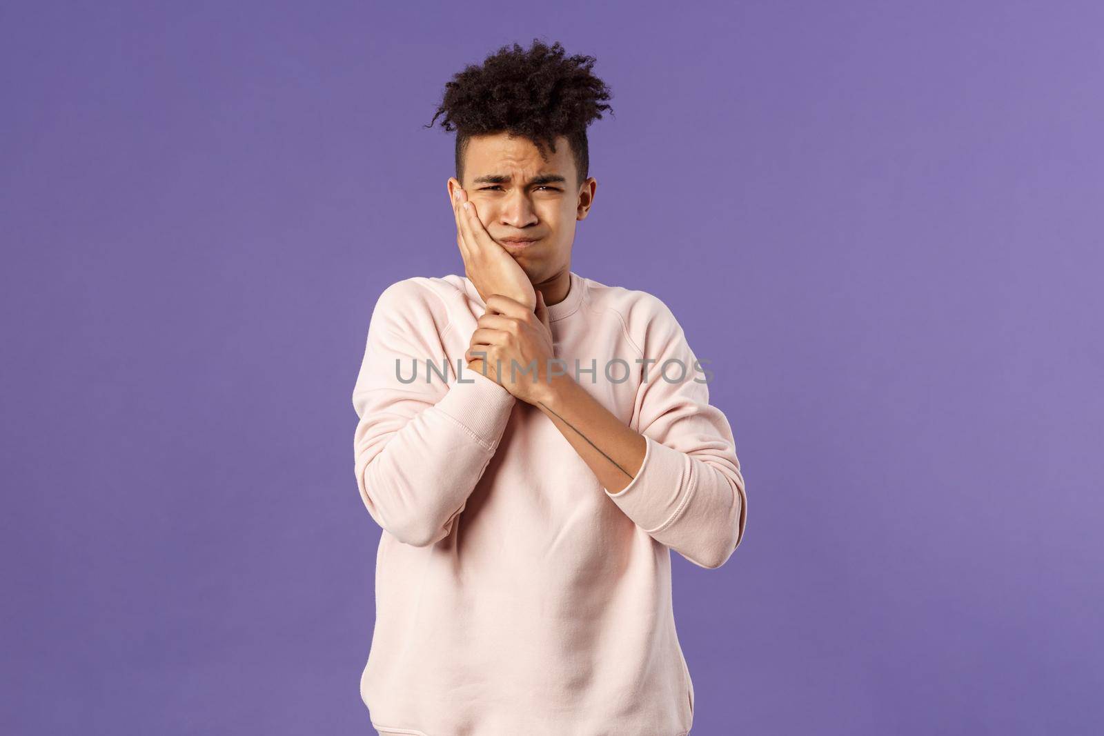 Portrait of troubled young man feeling painful ache in tooth, have toothache or decay, touching swallen cheek grimacing uneasy, need see dentist, waiting in line for appointment, purple background.