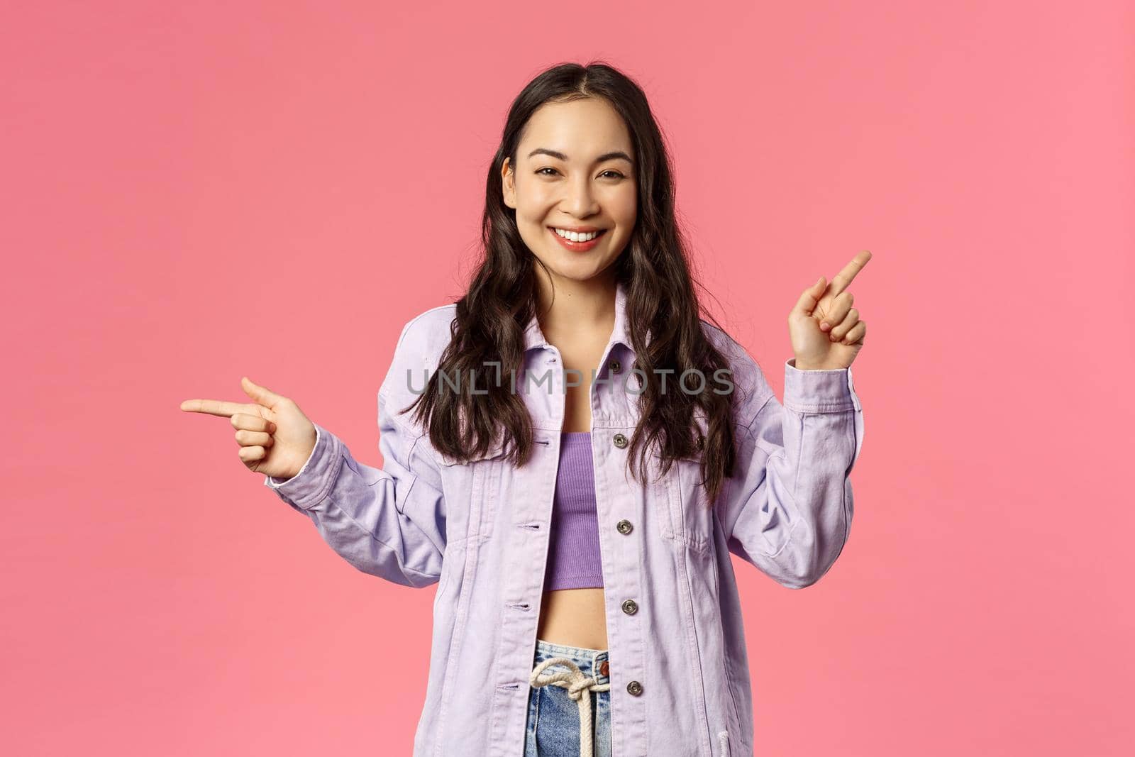 Portrait of stylish assertive cute korean girl giving choice, pointing fingers left and up, promote products, give advice where find useful links on online shops, internet stores, pink background by Benzoix