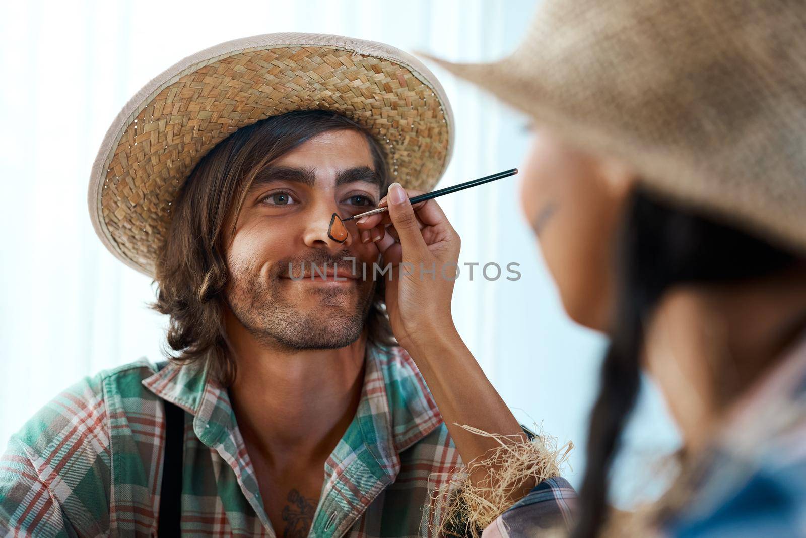 Who doesnt love a little Halloween makeup. a young woman applying makeup to a young man at home