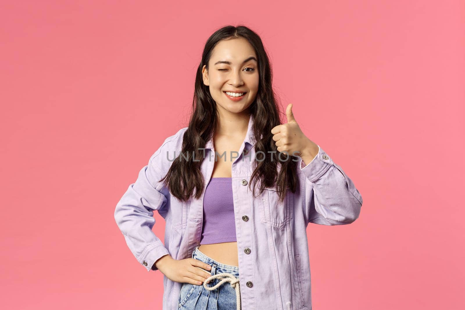 Cheerful good-looking, stylish woman wink and thumb-up as being pleased with service provides, recommend use company product or subscribe, smiling satisfied, pink background.