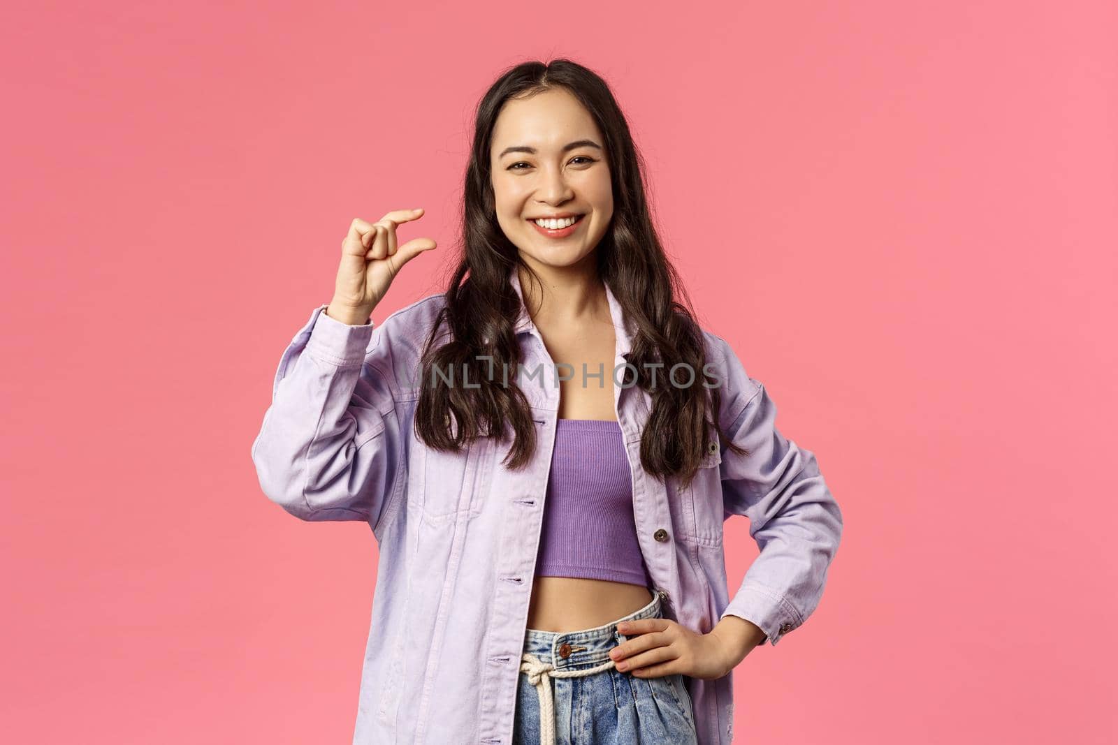 Little effort but big profit. Portrait of cheerful, attractive and carefree modern girl in denim jacket over crop-top, show something is small or tiny, laughing pleased smiling, pink background by Benzoix