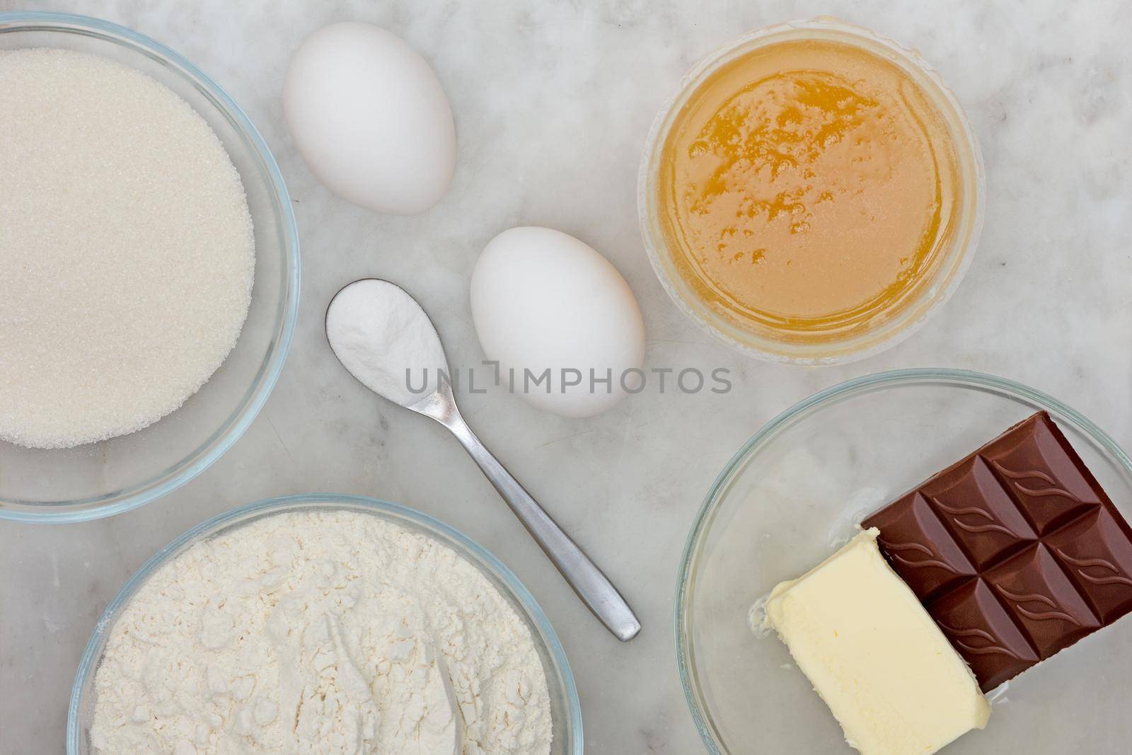 Top view sugar, flour, eggs, baking soda, butter, chocolate and honey as ingredients of chocolate cake medovik on marble background