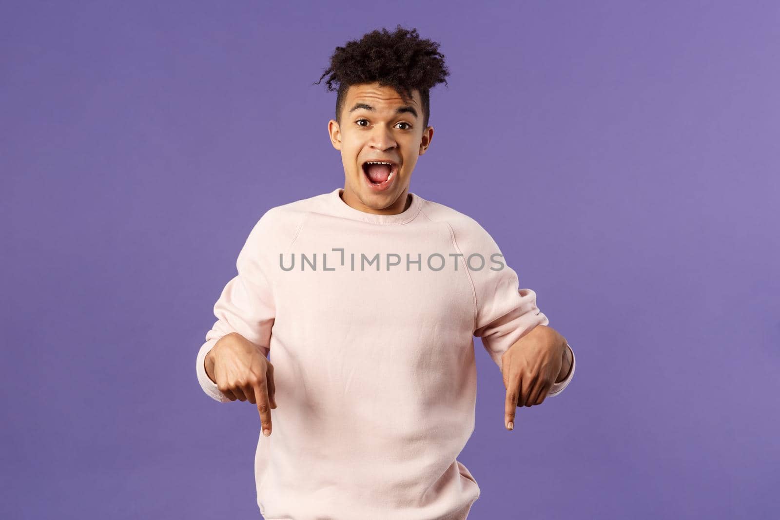 Portrait of handsome charismatic hispanic man inviting to subscribe, join courses or get this product right now, pointing fingers down, look camera fascinated and impressed, recommend promo by Benzoix