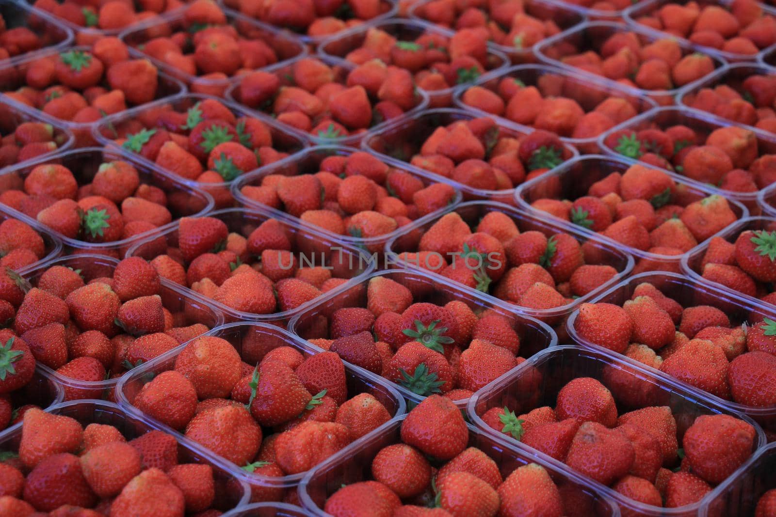 Strawberries in small plastic containers on a market stall