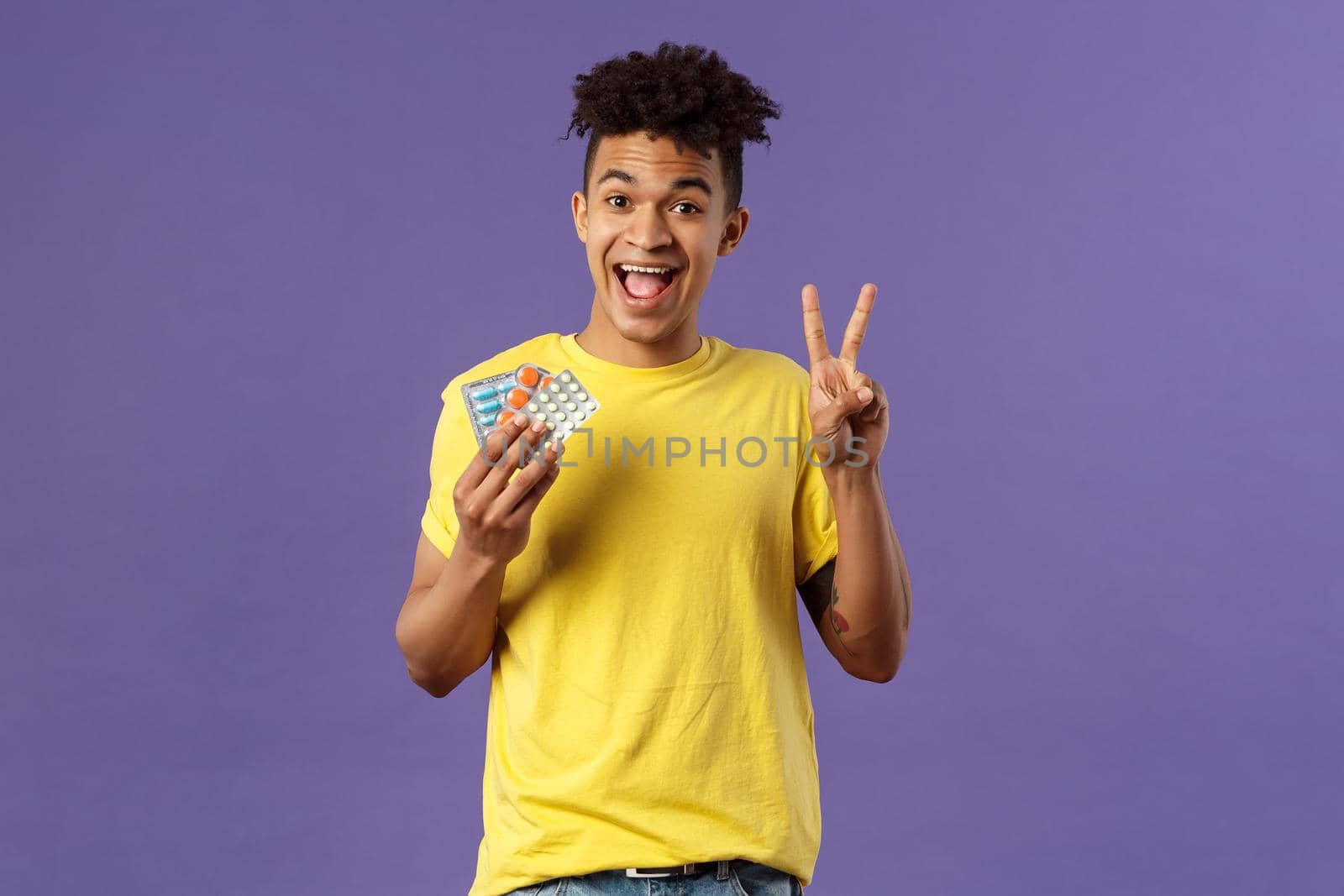 Health, influenza, covid-19 concept. Portrait of upbeat, healthy young man feel much better after taking vitamins or tablets, hold prescribed drugs, show peace sign, smiling pleased.