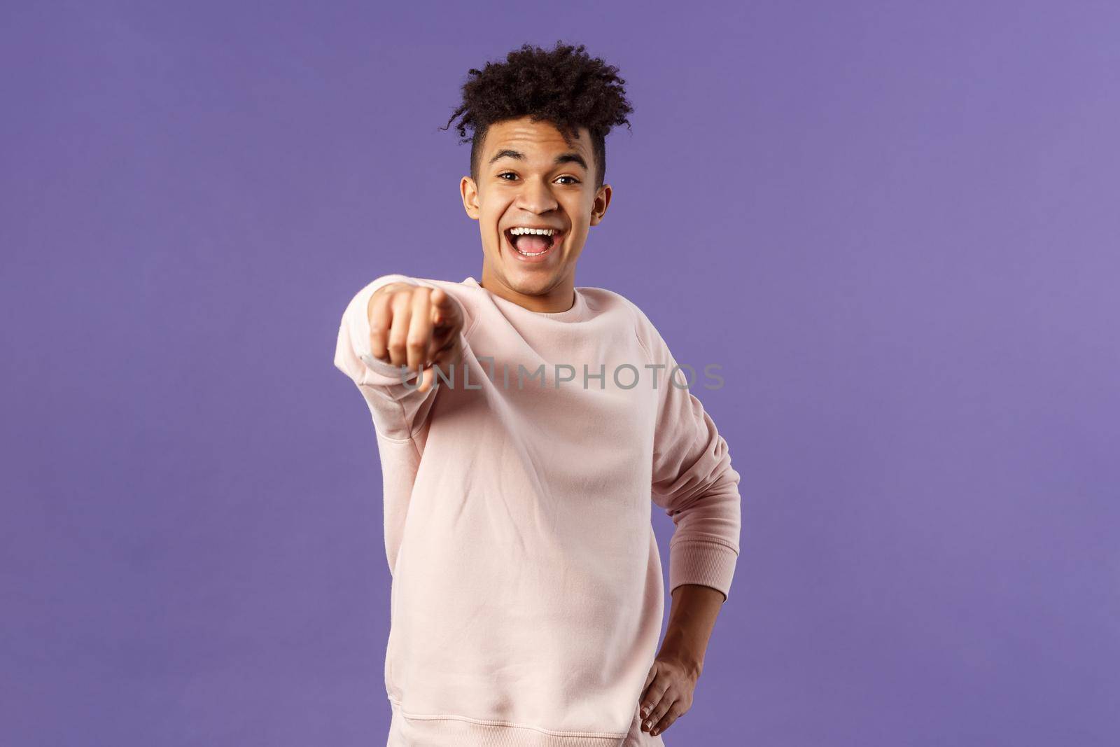 Portrait of outgoing happy hispanic male student making his choice, laughing over something extremely funny point finger at camera with amused smile, standing purple background.