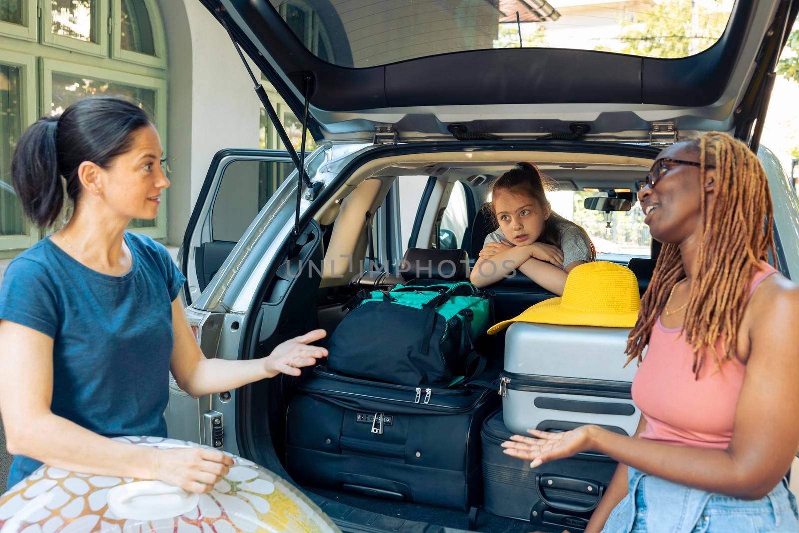 Diverse people travelling on vacation by car, leaving with family and friends to go to seaside with inflatable and luggage. Travel to sea with automobile, loading baggage and bags.