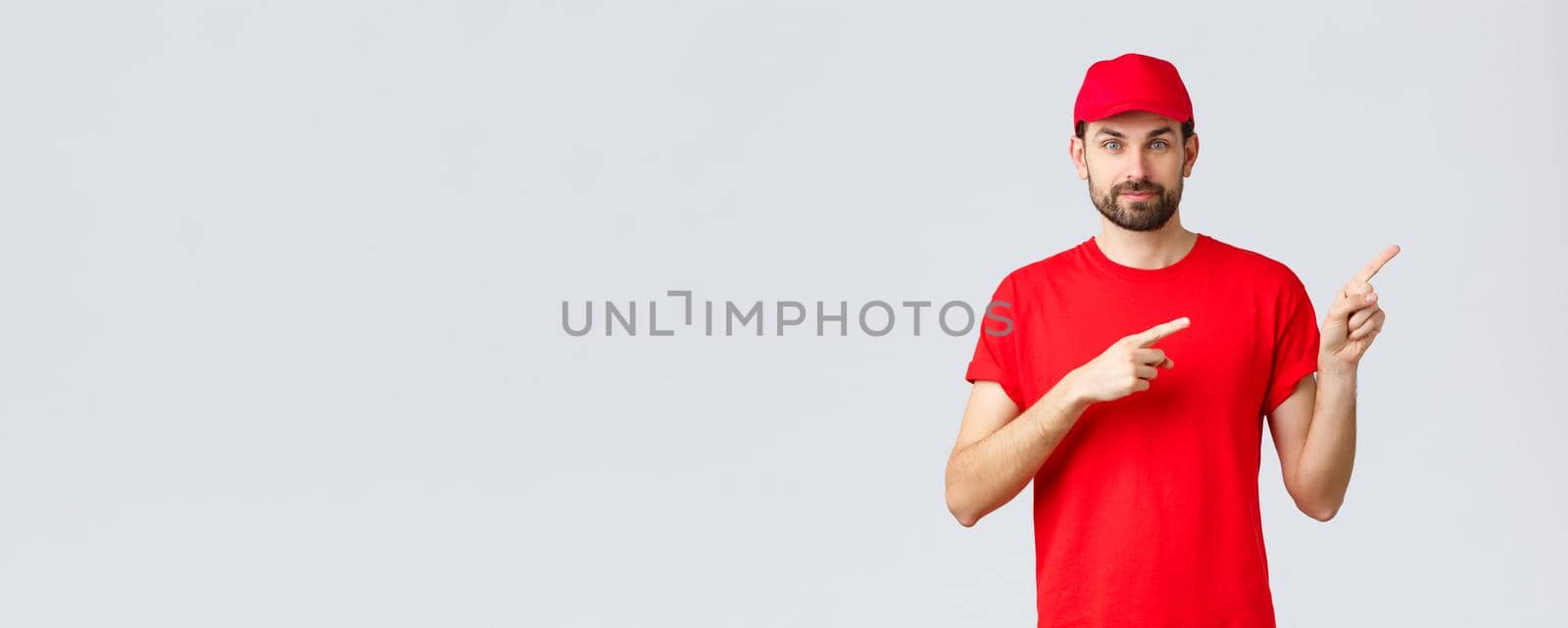Online shopping, delivery during quarantine and takeaway concept. Confident bearded courier in red uniform cap and t-shirt, smiling camera, give direction, pointing finger right, inform clients by Benzoix