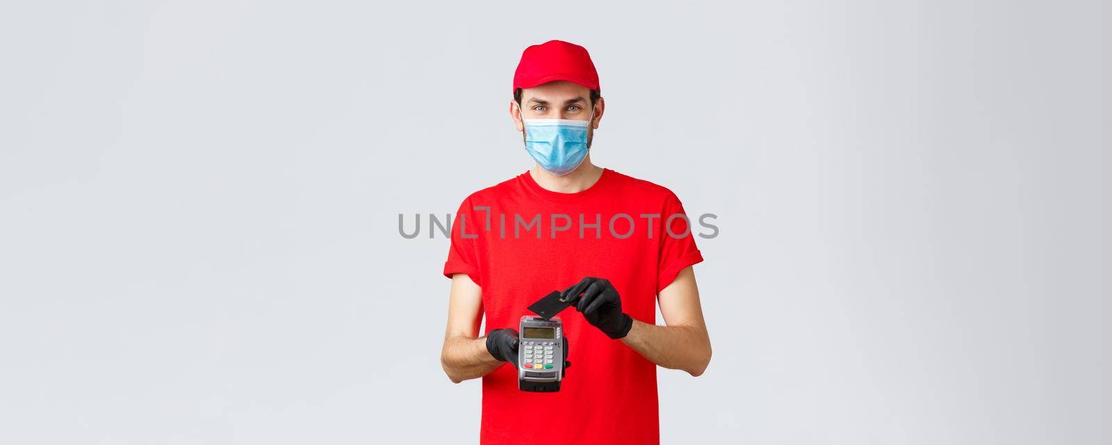 Contactless delivery, payment and online shopping during covid-19, self-quarantine. Courier provide safe paying orders, buying with credit card pressed to POS terminal, wear face mask and gloves by Benzoix
