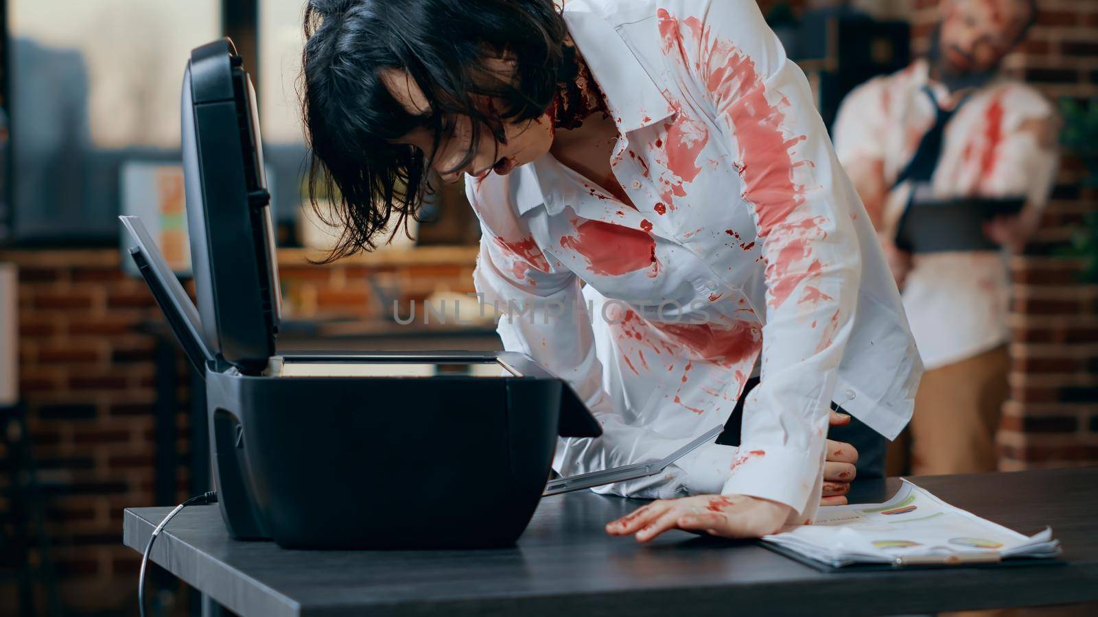 Dumb creepy looking zombie trying to use photocopy machine. Spooky evil brainless monster with deep and bloody scars and wounds while damaging scanner machine in company office workspace.