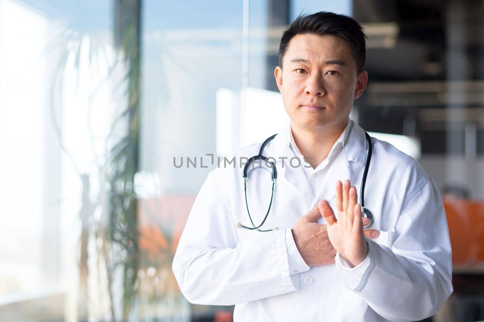 Serious and focused Asian doctor makes a video call from the clinic, a man in the office