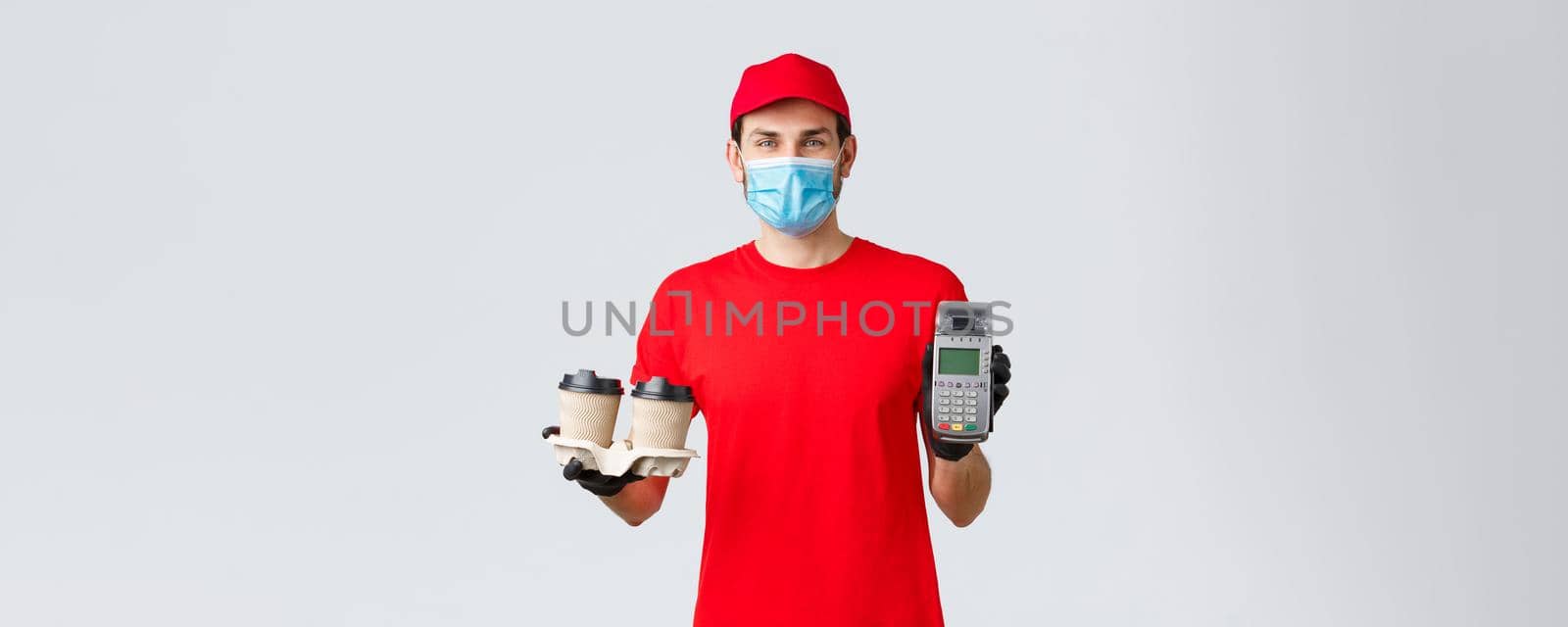 Takeaway, food and groceries delivery, covid-19 contactless orders concept. Friendly employee in red uniform, courier face mask and gloves, giving client POS terminal with coffee by Benzoix
