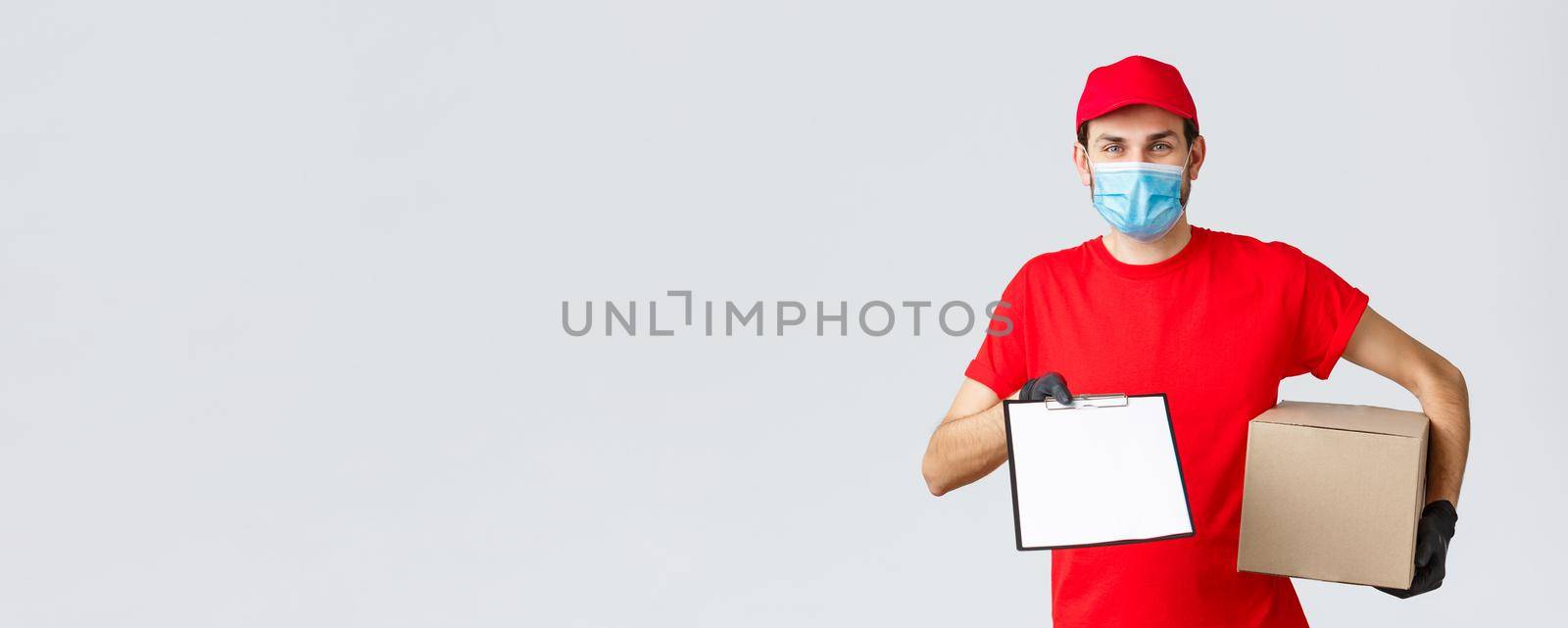 Packages and parcels delivery, covid-19 quarantine delivery, transfer orders. Friendly courier in red uniform, face mask and gloves, holding package box and give clipboard order sign form to client.