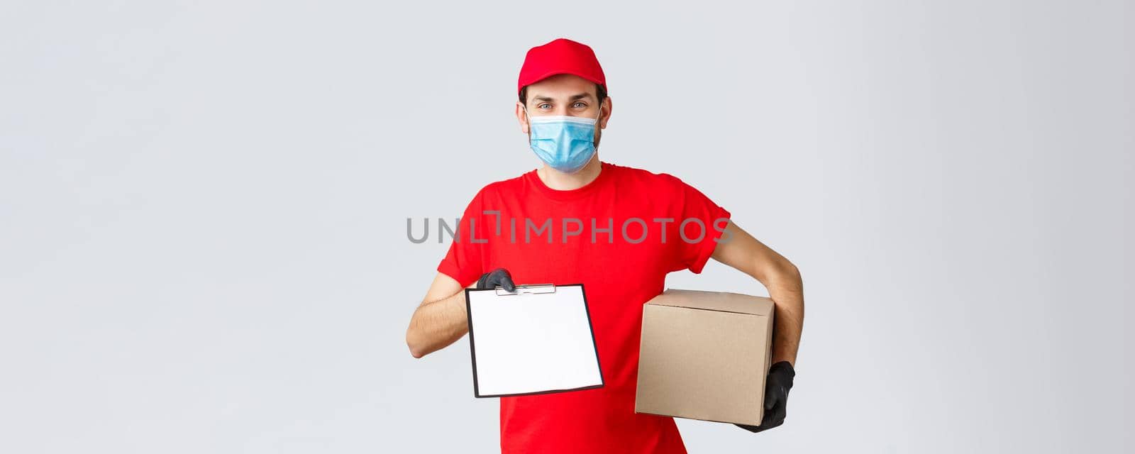 Packages and parcels delivery, covid-19 quarantine delivery, transfer orders. Friendly courier in red uniform, face mask and gloves, holding package box and give clipboard order sign form to client.