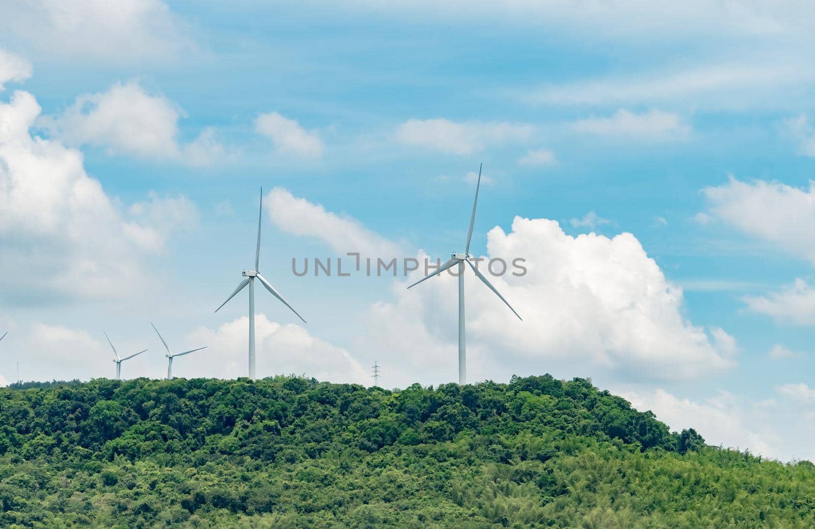 Wind energy. Wind power. Sustainable, renewable energy. Wind turbines generate electricity. Windmill farm on a mountain with blue sky. Green technology. Renewable resource. Sustainable development.