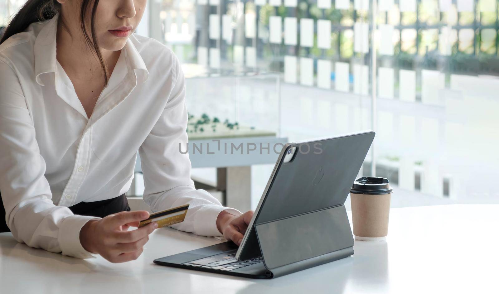 Young Asian businesswoman enjoy shopping online using credit card at a coffee shop..