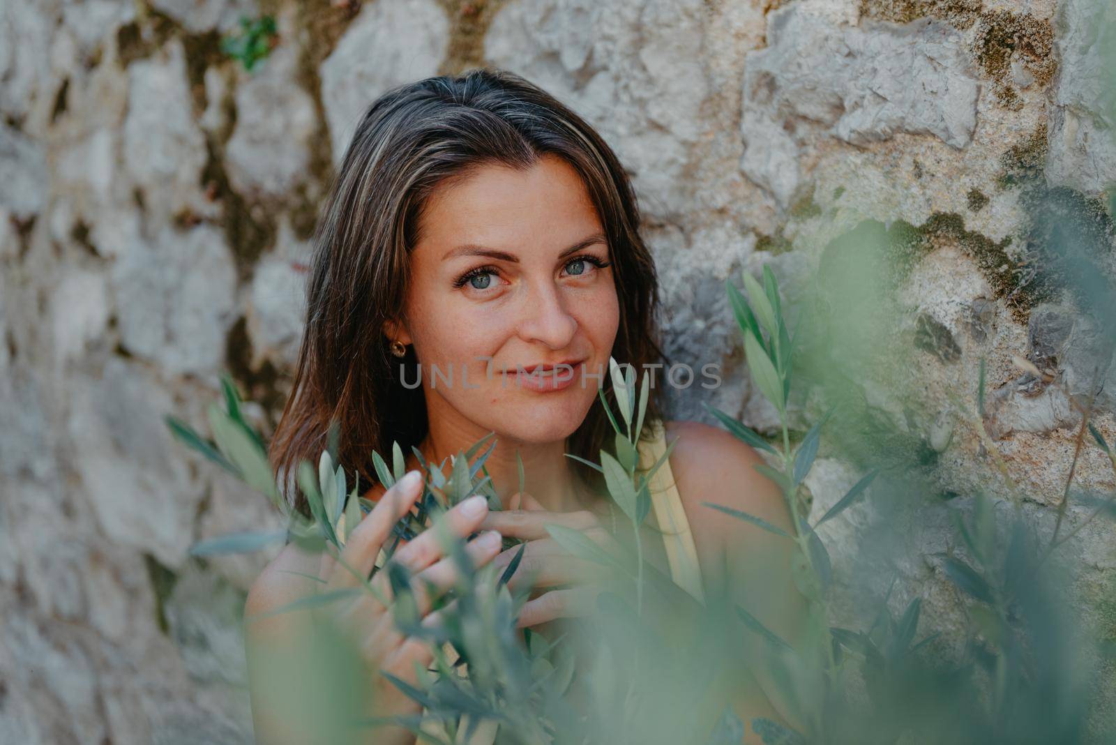 Girl tourist walking through ancient narrow street on a beautiful summer day in MEDITERRANEAN MEDIEVAL CITY , OLD TOWN bUDVA, MONTENEGRO. Young beautiful cheerful woman walking on old street at tropical town. Pretty girl looking at you and smiling