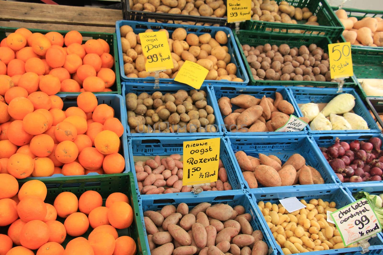 Fresh harvested potatoes on a market stall (text on tags: names and prices of various potatoes in Dutch, prices for various weight packages, all new harvest)