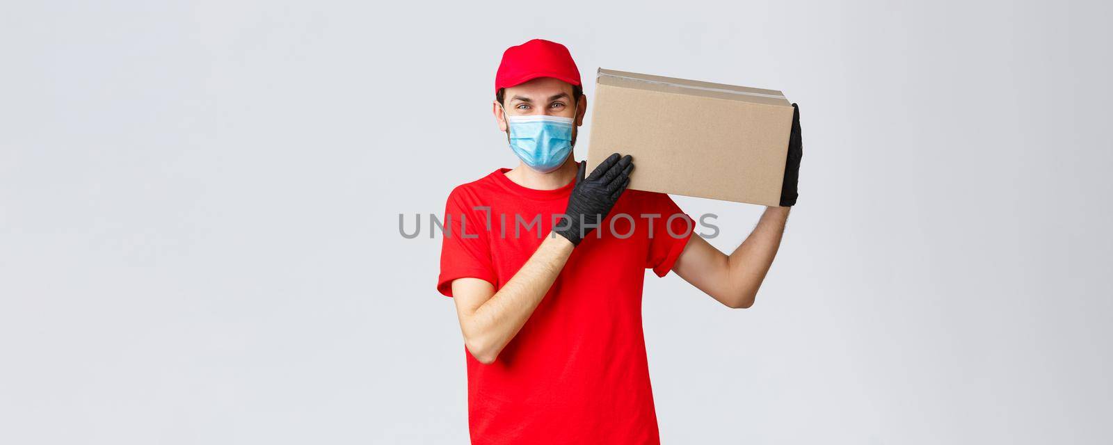 Packages and parcels delivery, covid-19 quarantine delivery, transfer orders. Friendly courier bring order to client house, holding package box on shoulder, wear face mask and rubber gloves.