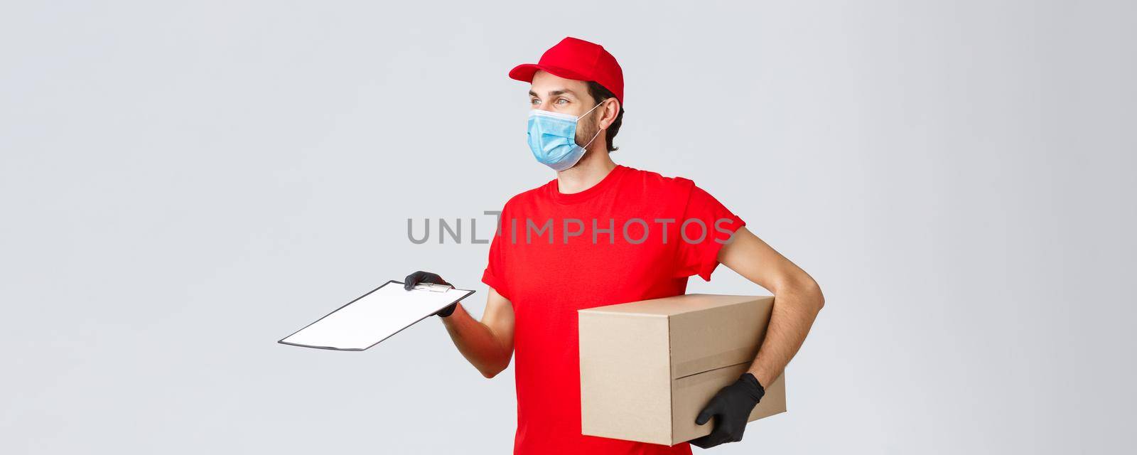 Packages and parcels delivery, covid-19 delivery, transfer orders. Profile of friendly courier in red uniform in face mask and gloves, bring order, hold box and give form for client to sign.