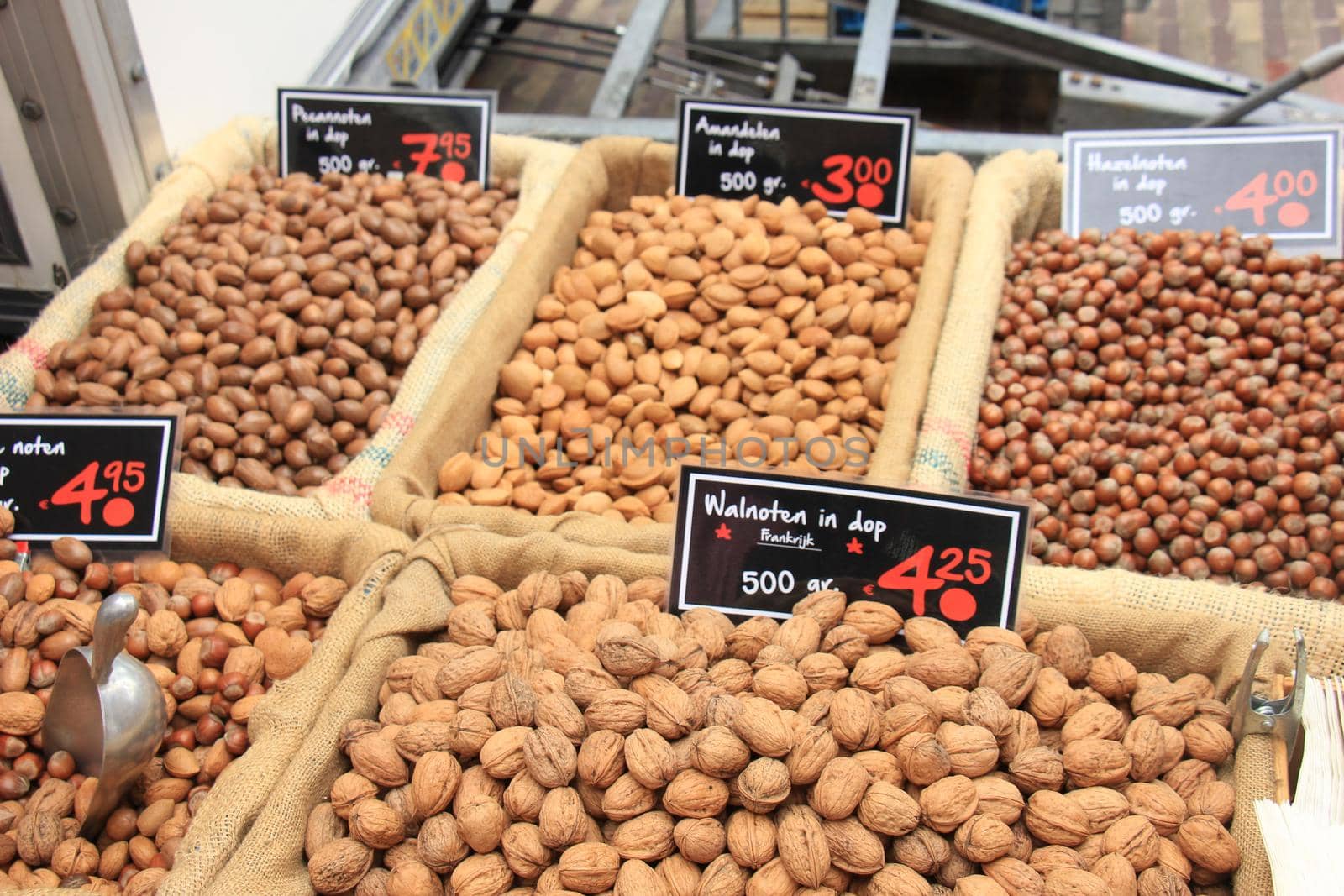 Fresh unpealed nuts on a market stall (text on tags: names and prices of various nuts in Dutch, walnuts, Pecan, almonds and hazel)