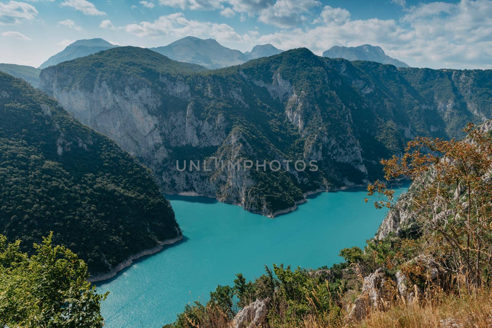 The concept of eco-tourism and active recreation. National Park. Mountain Emerald lake in the wooded mountains. Sunny day in autumn.