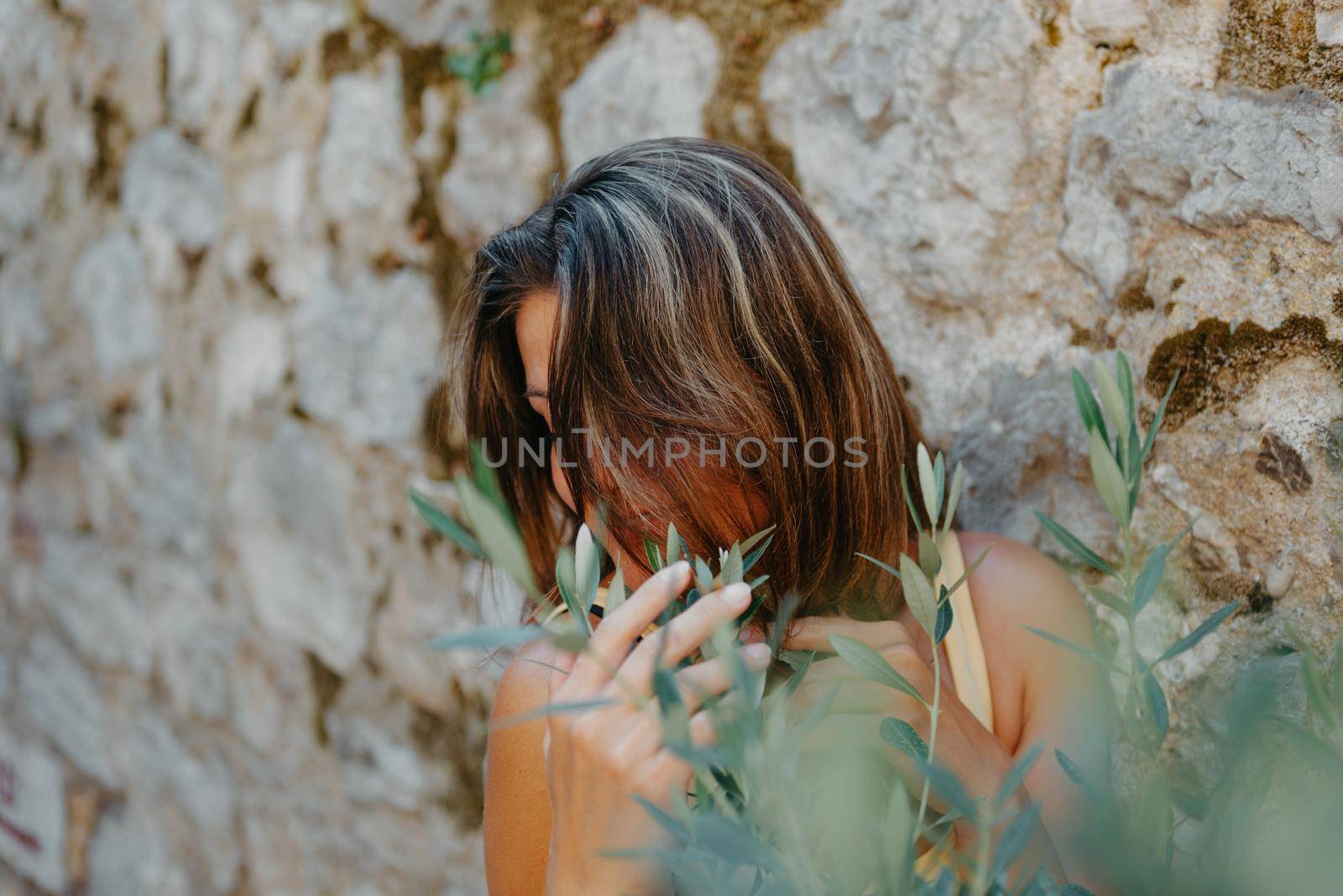 Girl Tourist Walking Through Ancient Narrow Street On A Beautiful Summer Day In MEDITERRANEAN MEDIEVAL CITY, OLD TOWN BUDVA, MONTENEGRO. Young Beautiful Cheerful Woman Walking On Old Street At Tropical Town. Pretty Girl Looking At You And Smiling by Andrii_Ko