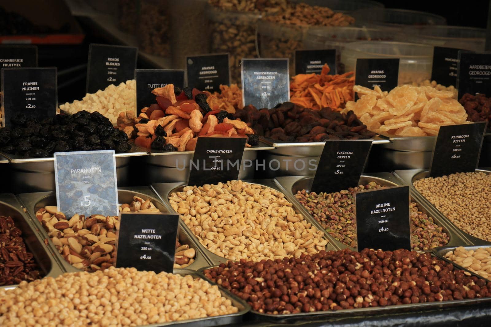 Fresh nuts on a market stall (text on tags: names and prices of various nuts in Dutch, white and brown hazel nuts, pistacho, para and cashew)