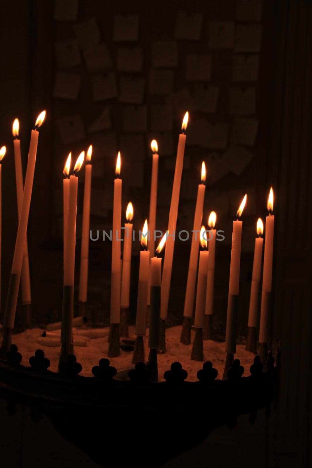 Long thin candles in a roman catholic church by studioportosabbia