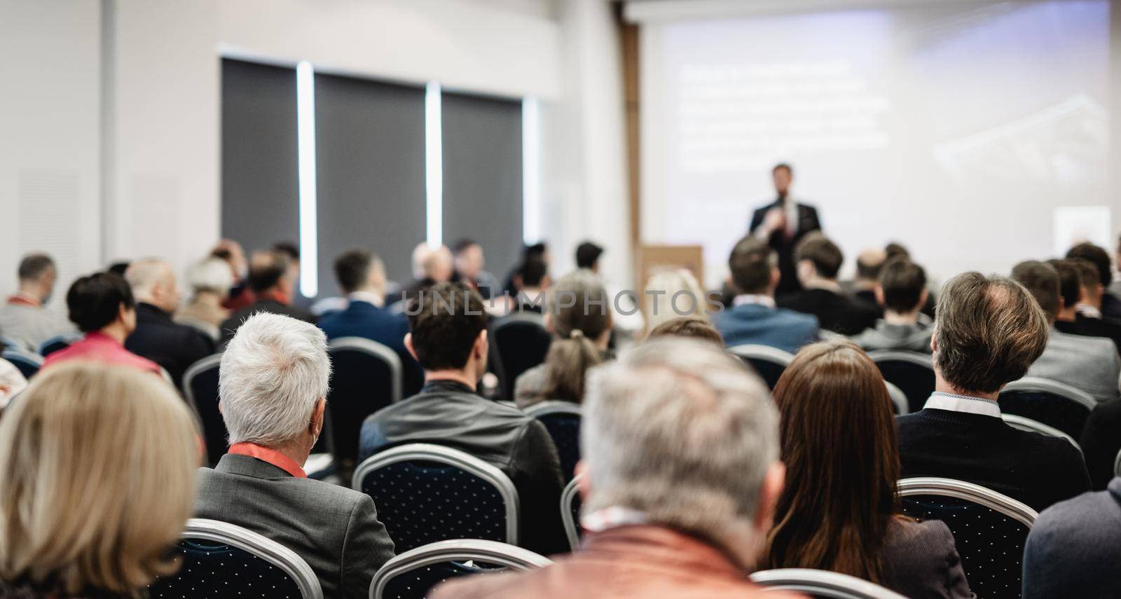 Speaker giving a talk in conference hall at business event. Rear view of unrecognizable people in audience at the conference hall. Business and entrepreneurship concept