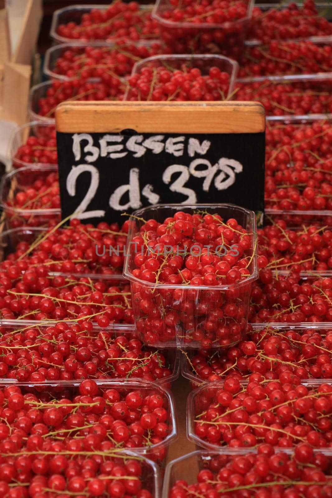 red currants in small boxes on a market stall (text on tag: product and price information in Dutch)