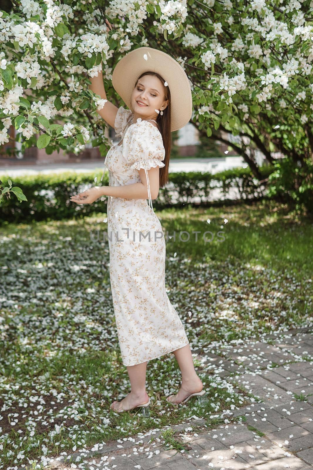 An attractive long-haired woman walks in the spring in the park of blooming apple trees. Spring portrait of a woman