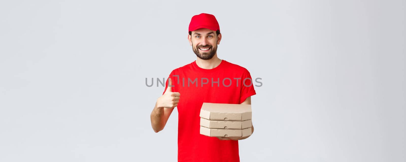 Food delivery, quarantine, stay home and order online concept. Friendly smiling bearded courier in red uniform cap and t-shirt, recommend their service or restaurant, give pizza to customer by Benzoix