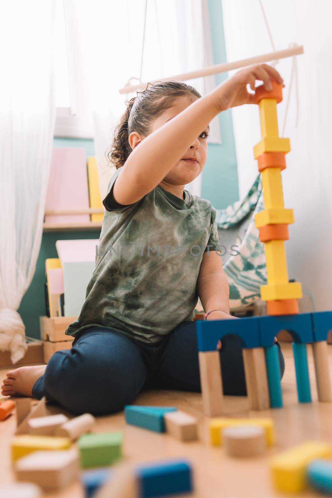 concentrated little girl playing happy in the floor with colorful wooden building block toys at home or kindergarten, educational toys for creative children